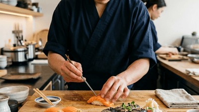 Fresh sushi being prepared with salmon nigiri and maki rolls on bamboo board